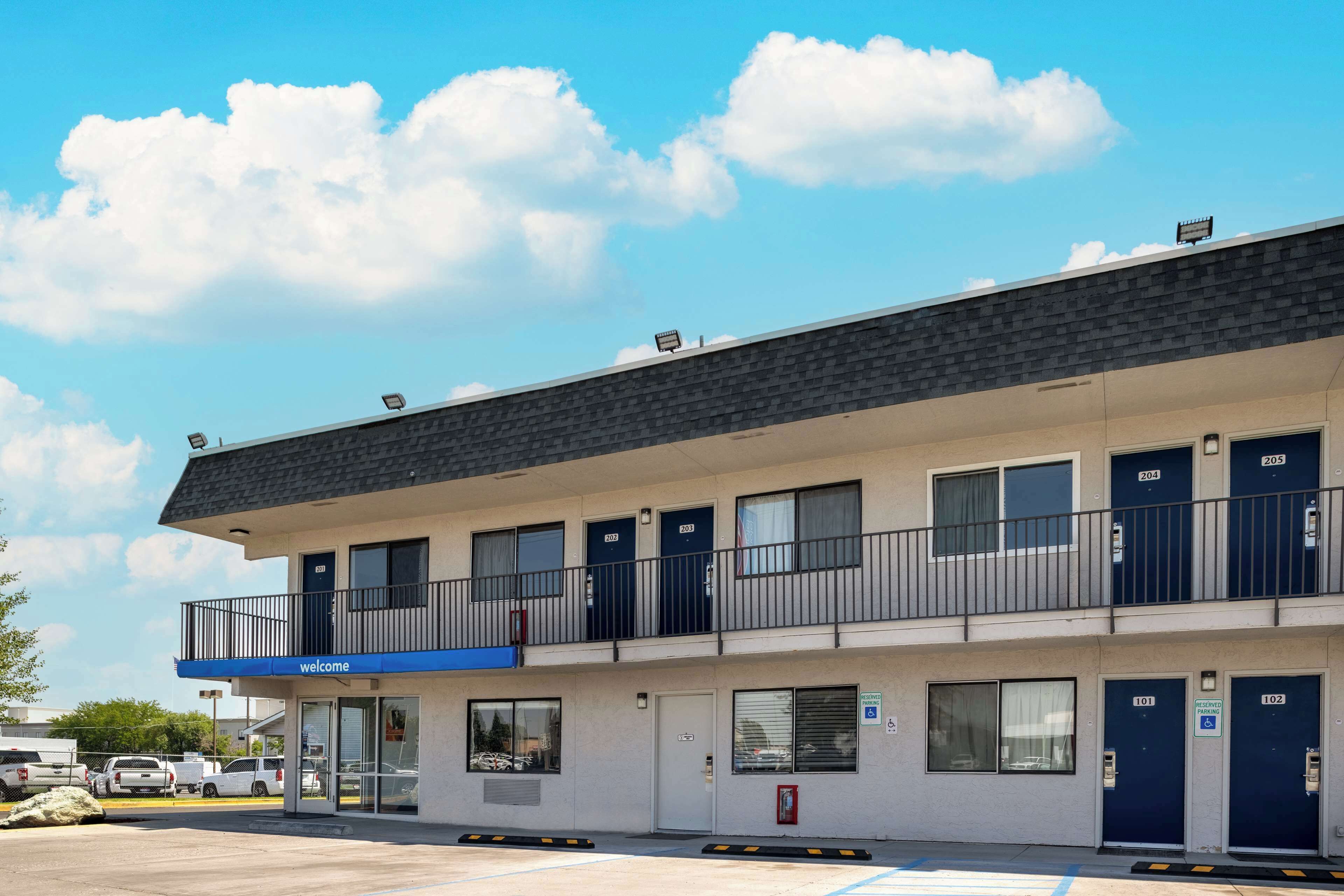 A two-story motel with a 'welcome' sign, numbered rooms, and a parking lot.