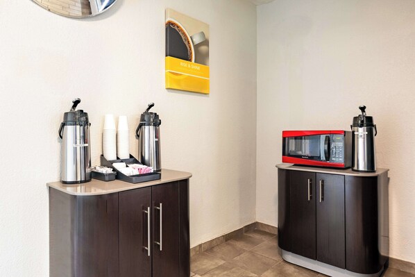 A hotel room with a kitchenette area featuring a coffee maker, a microwave, and a coffee dispenser on a cabinet. - Motel 6 Twin Falls, ID (Twin Falls)