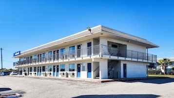 A two-story motel with a flat roof, multiple balconies, and a 'Welcome' sign.