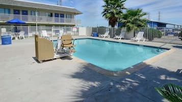 Een buitenzwembad, parasols bij het zwembad en ligstoelen