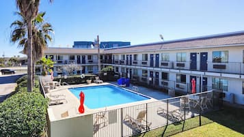 A motel with a swimming pool, multiple balconies, and a fenced patio area.