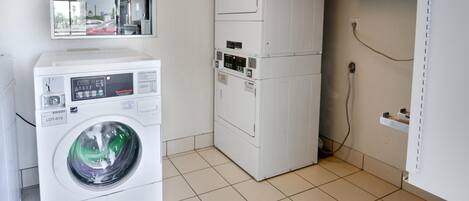A laundry room with a front-loading washing machine and stacked dryers.