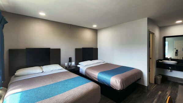 A hotel room with two beds, a bathroom with a sink and mirror, and a phone on the nightstand. - Motel 6 Galveston, TX (Galveston)