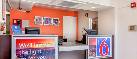 A hotel reception desk with a sign that reads "We'll leave the light for you."
