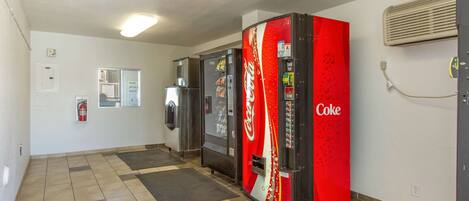 En korridor med försäljningsautomater, inklusive en automat som säljer Coca-Cola, och en brandsläckare på väggen.