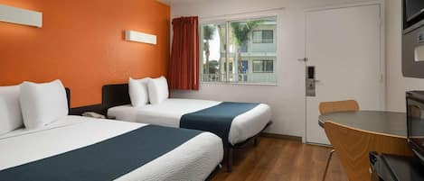 A hotel room with two beds, a desk, a chair, a TV, and a window with curtains.
