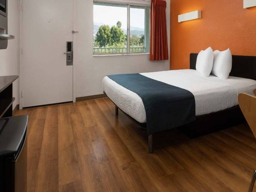 Habitación de hotel con cama, escritorio, silla, ventana con vistas y puerta.