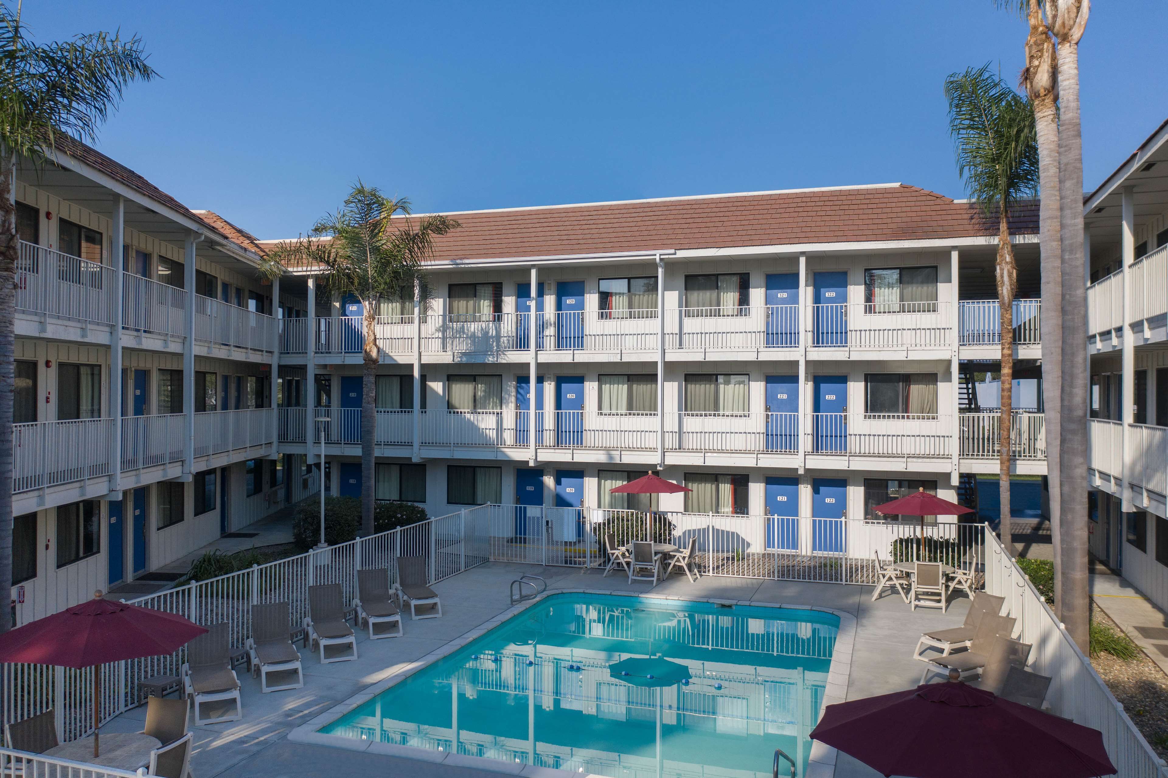Ein Hotel mit Poolbereich, mehreren Balkonen und blauem Himmel.