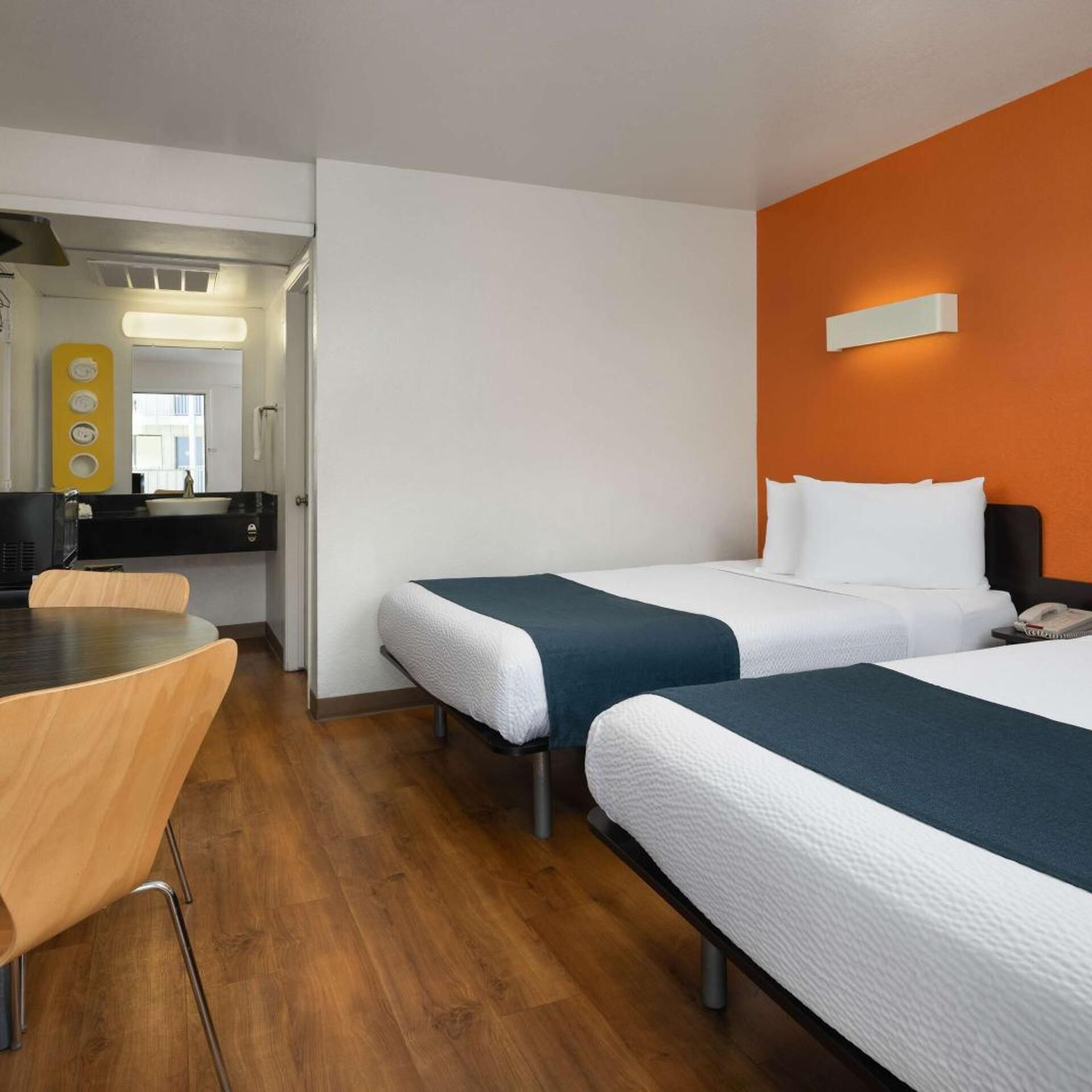 Una habitación de hotel con dos camas, una mesa de comedor y un baño moderno.
