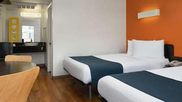 Una habitación de hotel con dos camas, una mesa de comedor y un baño moderno.