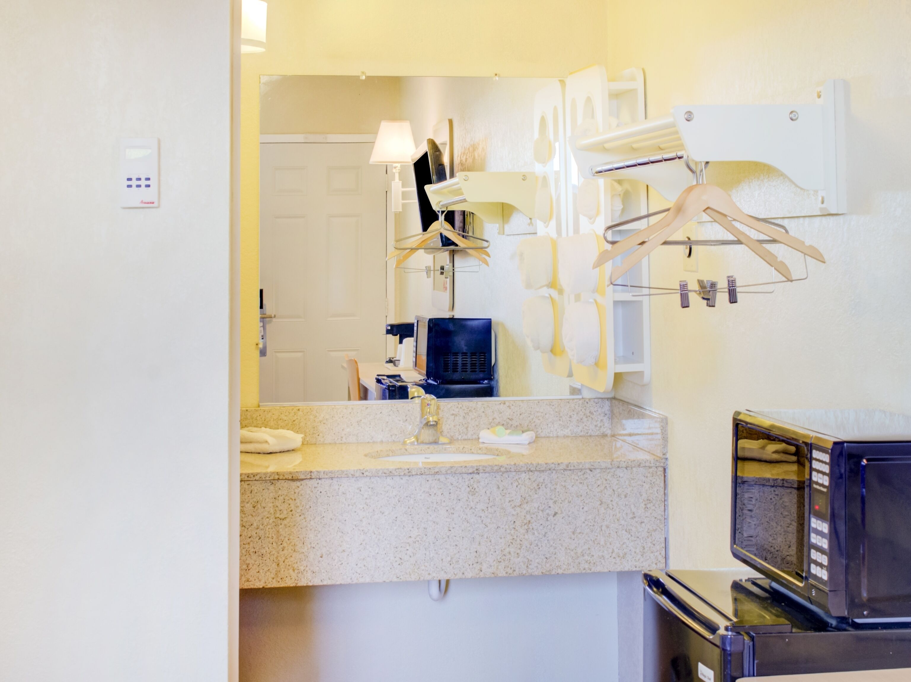 Une salle de bain d’hôtel équipée d’un lavabo, d’un miroir, d’un porte-serviettes et d’une machine à café.