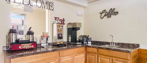 A kitchen with a coffee station, a welcome sign, and a coffee sign on the wall.
