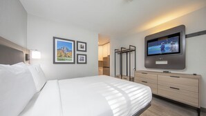 Ein modernes Hotelzimmer mit einem großen Bett, einem flachbildfernseher an der Wand und einer Holzkommode.