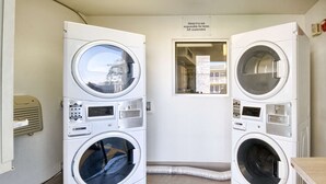 Dos lavadoras de carga frontal apiladas en una habitación con un cartel que dice 'Motel 6 no se hace responsable por objetos abandonados'.