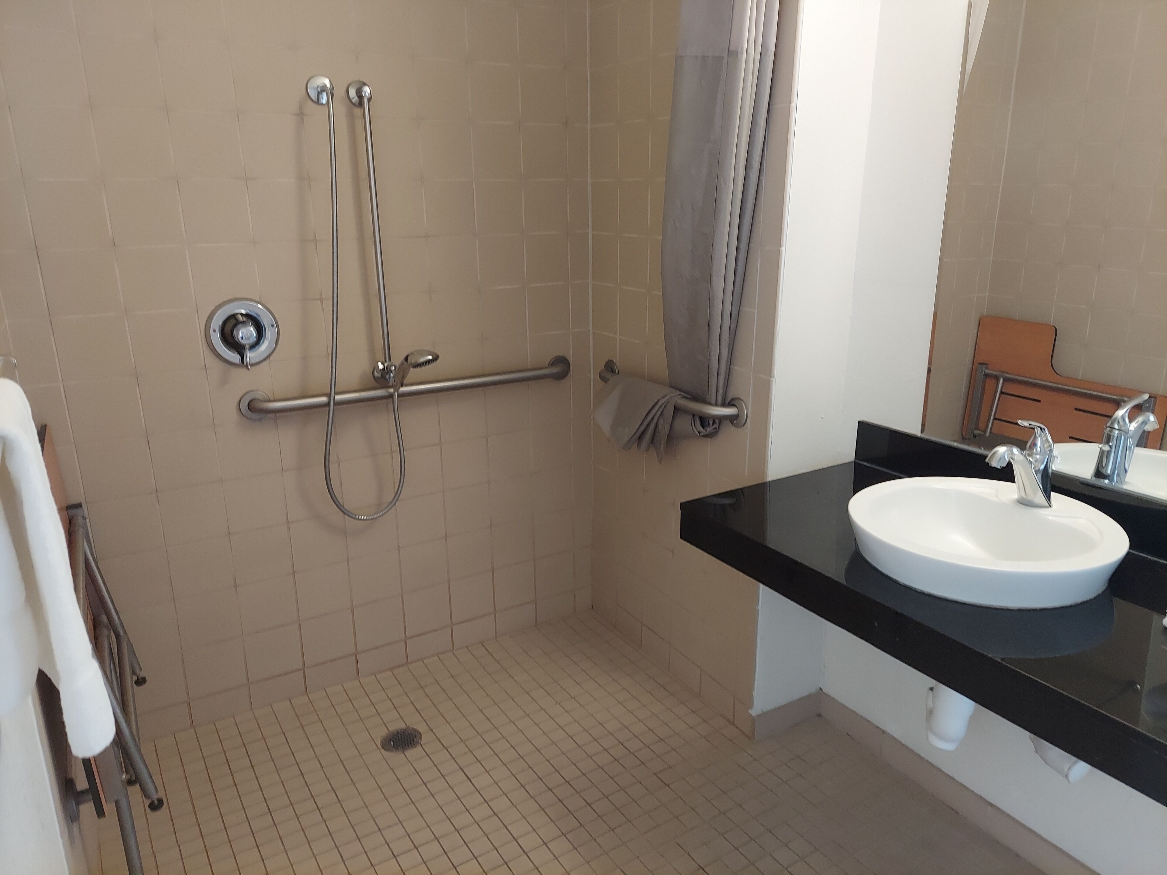 A bathroom with a shower, grab bar, and sink.
