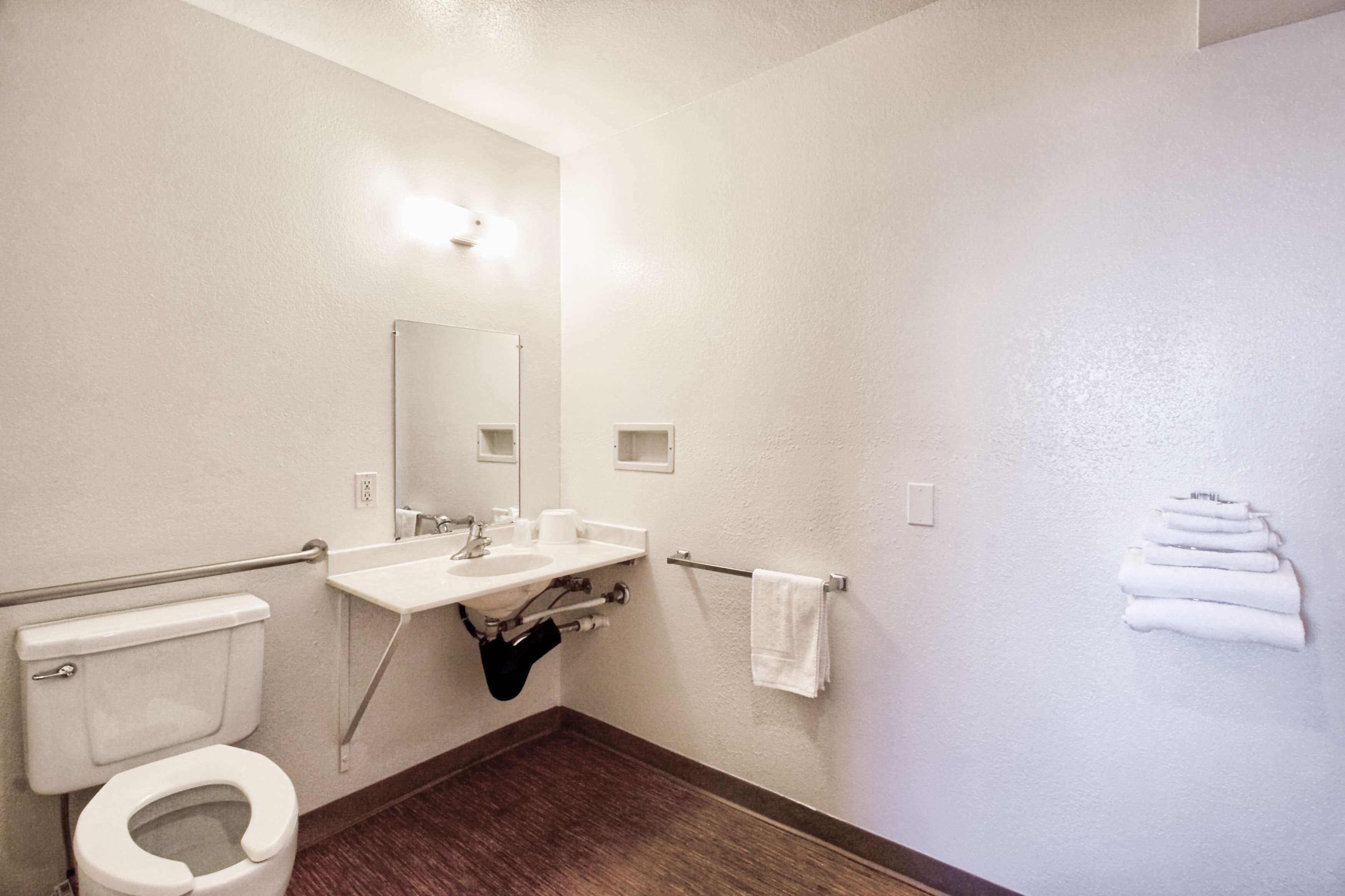A bathroom with a toilet, sink, mirror, towel rack, and a shower area.