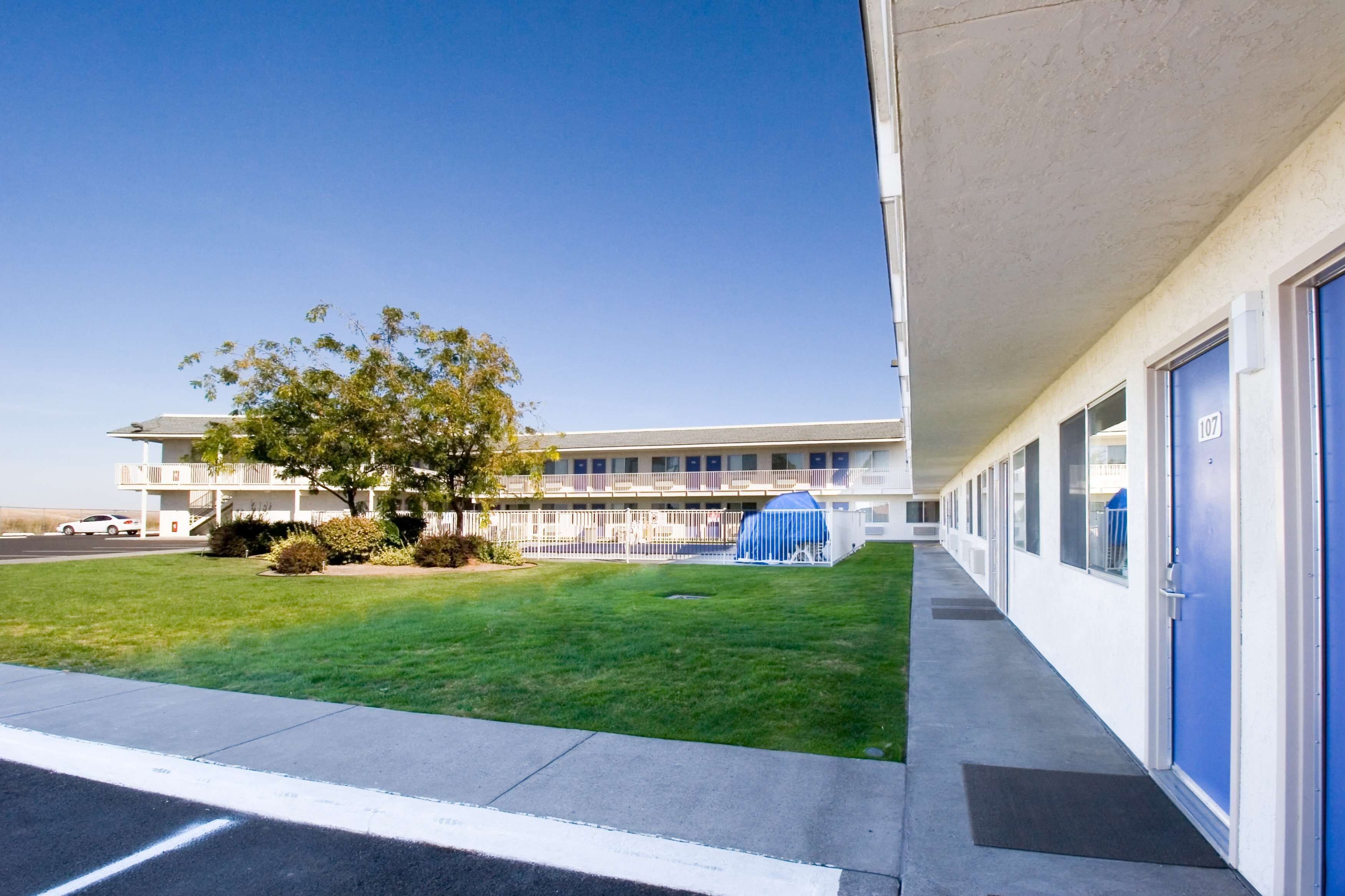 A building with a row of rooms, a grassy area, and a tree.
