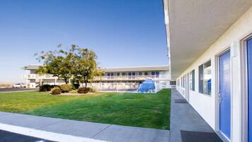 A building with a row of rooms, a grassy area, and a tree.