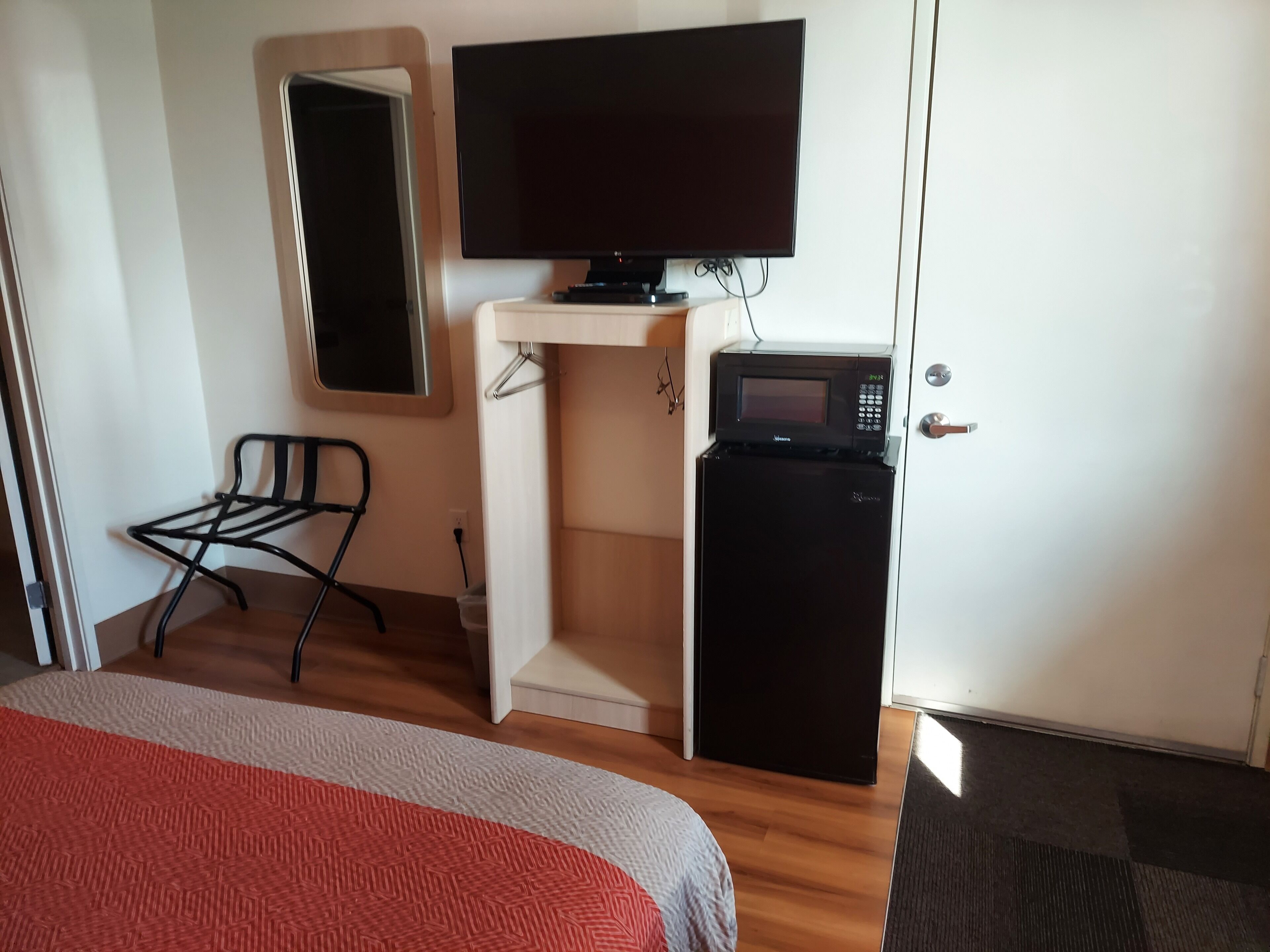 Une chambre d’hôtel équipée d’un lit, d’une télévision, d’un four à micro-ondes et d’un petit réfrigérateur.