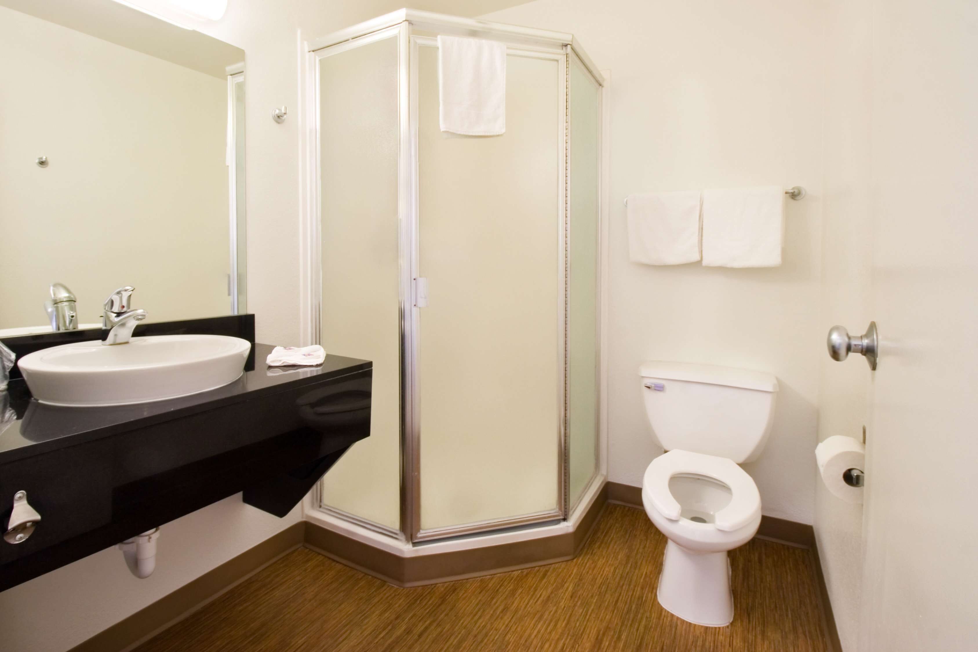 Un baño con ducha de vidrio, lavamanos, inodoro y espejo.