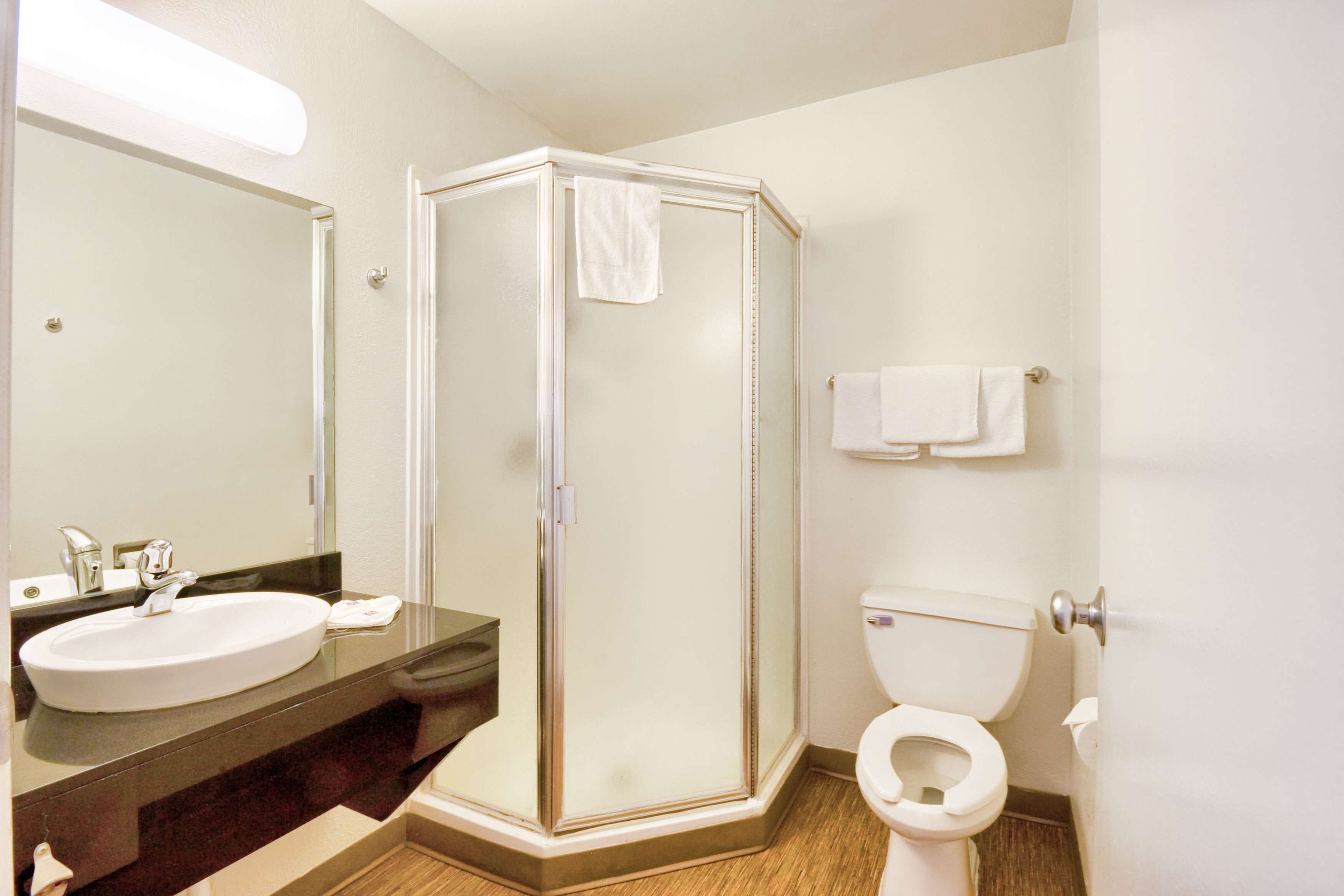 Een badkamer met een douche met glazen wand, een wastafel en een toilet.