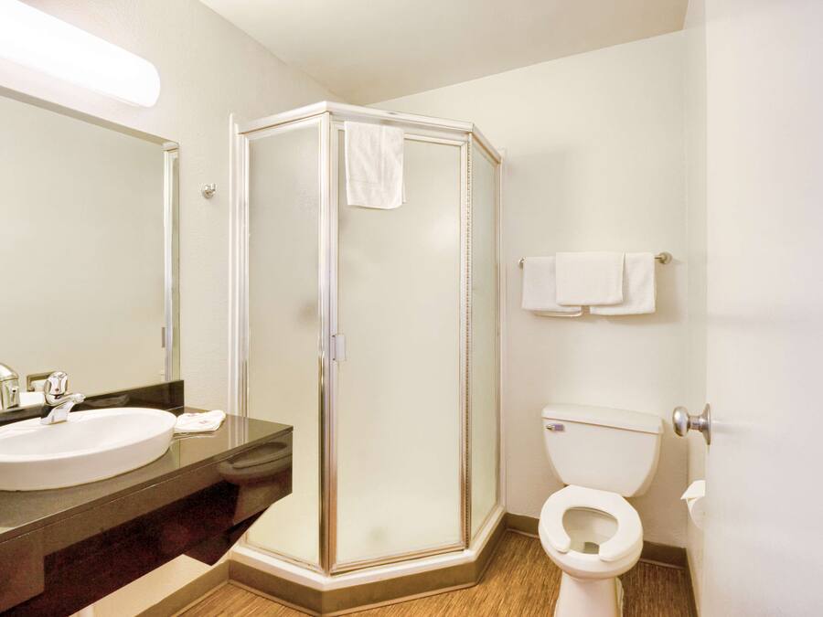 Een badkamer met een douche met glazen wand, een wastafel en een toilet.