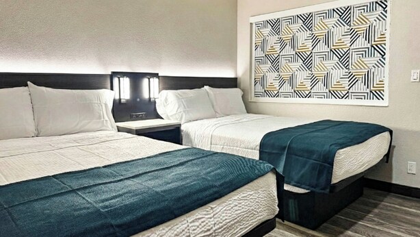 A hotel room with two beds, a nightstand, and a wall-mounted light fixture. - Motel 6 Atascadero, CA (Atascadero)
