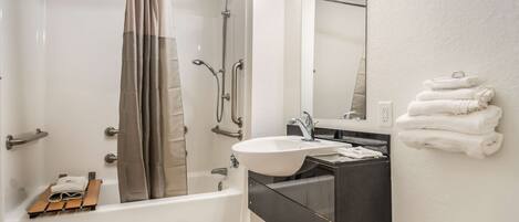 A modern bathroom with a bathtub, shower, sink, and a mirror.