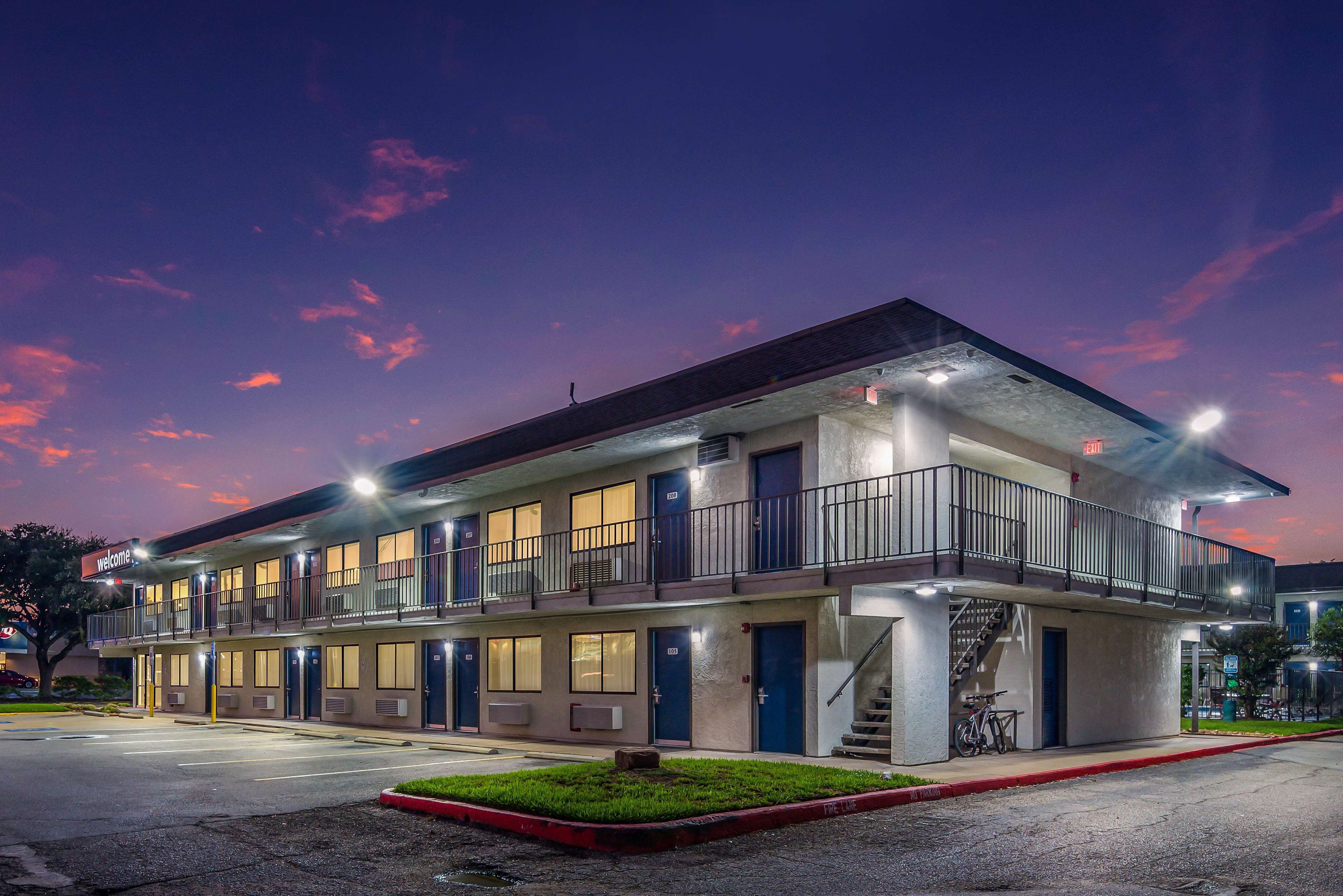 A two-story motel with multiple rooms, a balcony, and a staircase leading to an upper level.