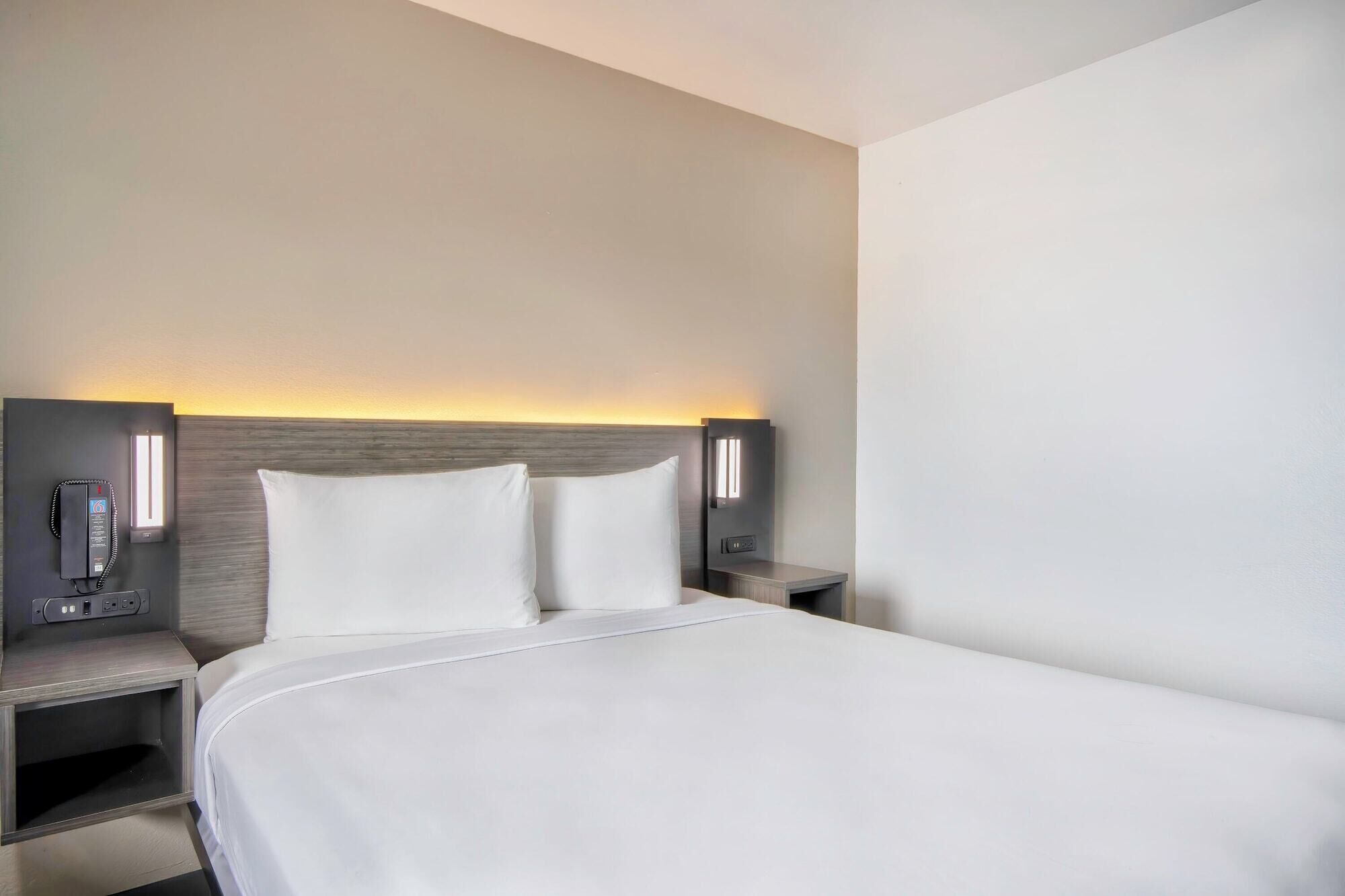 Habitació d'hotel amb un llit gran, dues taules de nit i una làmpada penjada a la paret.