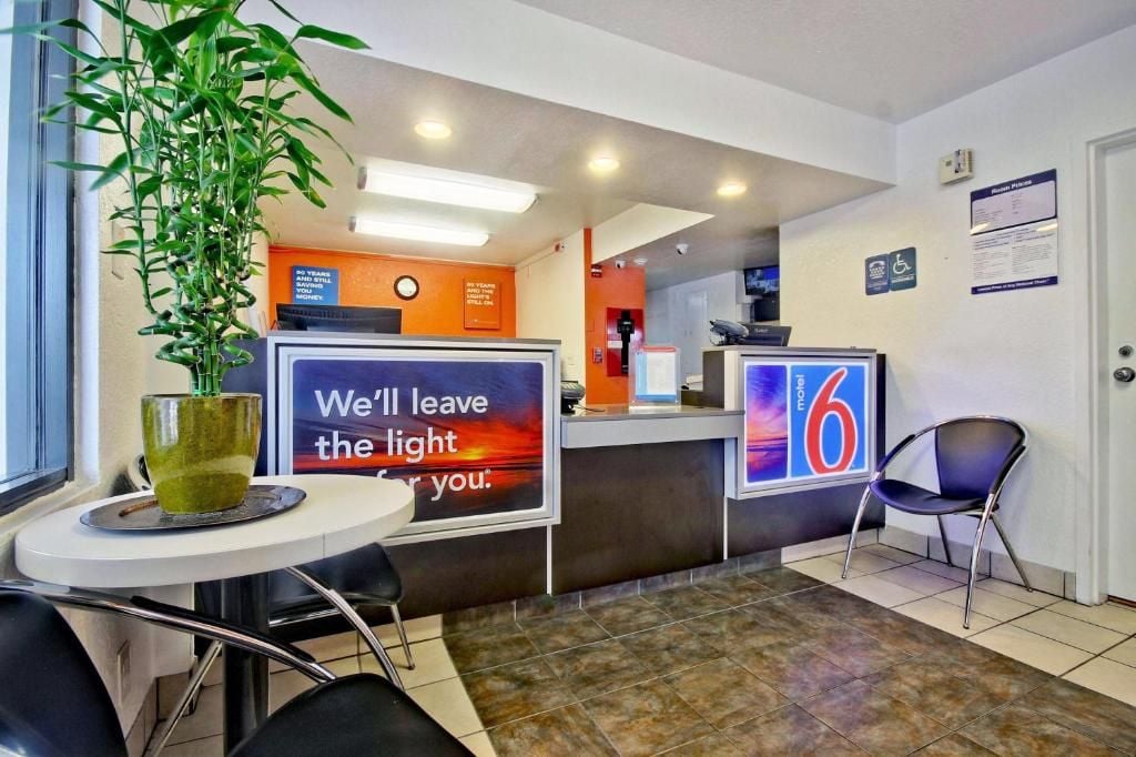 A hotel reception area with a reception desk, a plant, a sign with a message, and a wheelchair-accessible sign.