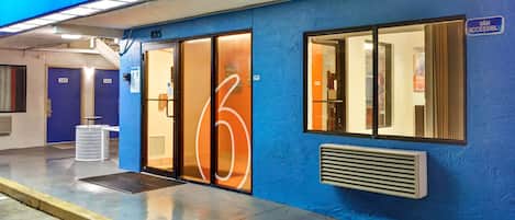 A blue building with a 'welcome' sign, numbered doors, and a 'van accessible' sign.