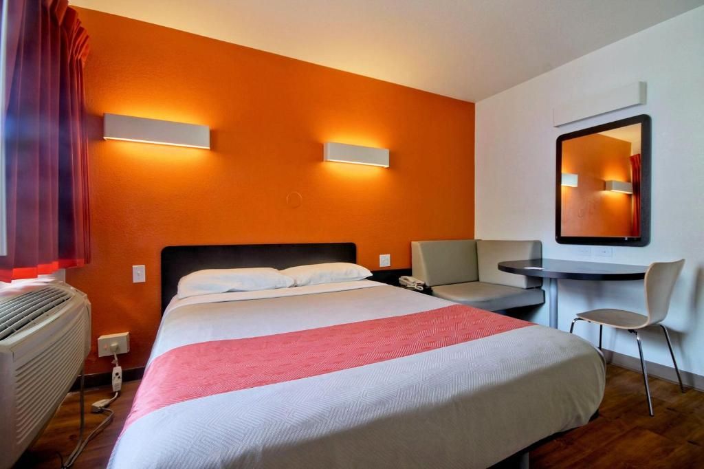 Ein Hotelzimmer mit Bett, Schreibtisch, Stuhl, Spiegel und Heizung.