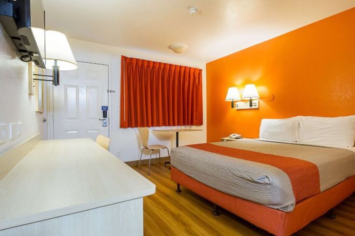 A hotel room with a bed, a desk, and a chair.
