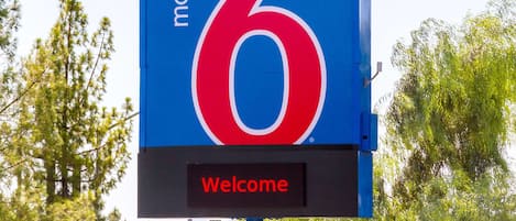 Señal de motel con el número 6 y un mensaje de bienvenida.