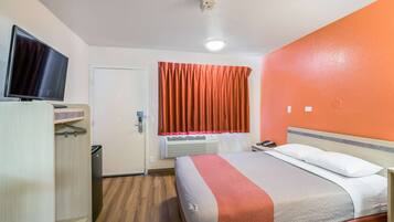 Habitación de hotel con cama, televisión, armario, ventana con cortinas, unidad de aire acondicionado y puerta.