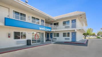A two-story building with a blue 'Welcome' sign, a fire extinguisher, and a wheelchair-accessible ramp.