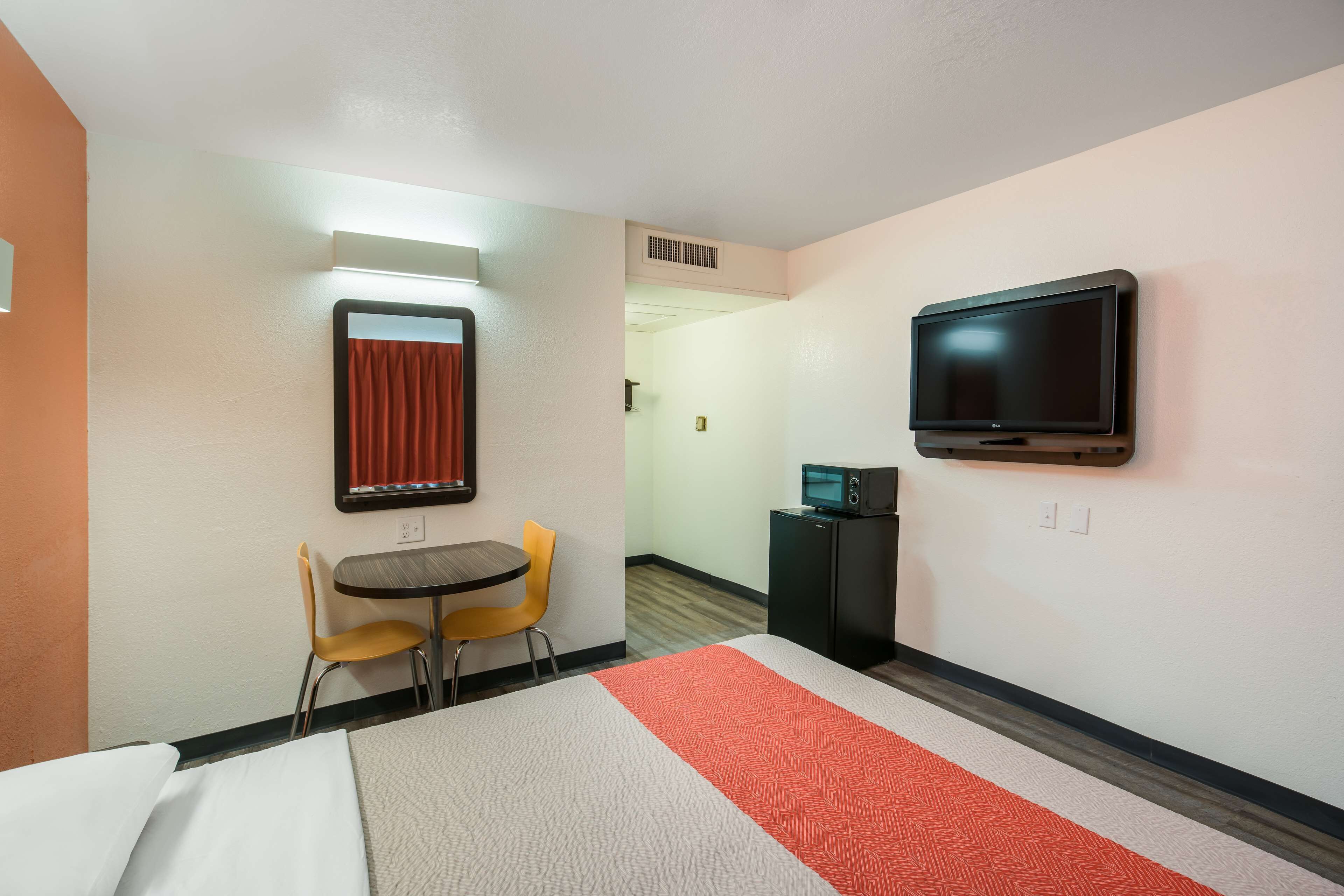 Una habitación de hotel con una cama, un escritorio con dos sillas, un televisor y un microondas.