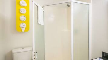 Un baño con cabina de ducha de vidrio, inodoro y lavabo con espejo.