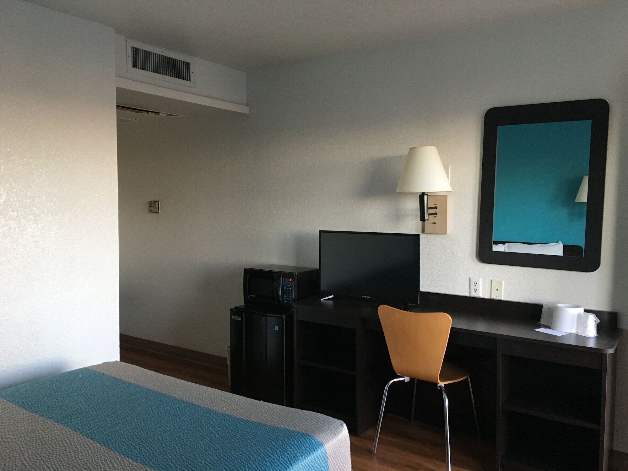 Ein Hotelzimmer mit Bett, Schreibtisch mit Computer, Stuhl, Lampe und Fernseher.