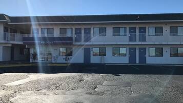 Um motel de dois andares com um letreiro de 'Welcome', quartos numerados e um estacionamento.