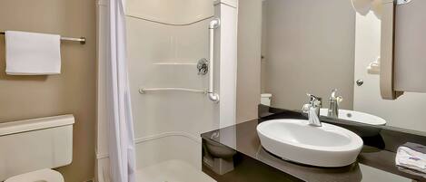 A modern bathroom with a walk-in shower, a toilet, and a sink with a mirror.