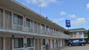 A motel with a blue sign, handicap accessible rooms, and a parking lot. - Super 7 Inn (Bossier City)