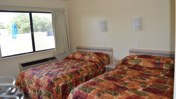 A hotel room with two beds, a window with curtains, and a view of the outside. - Super 7 Inn (Bossier City)