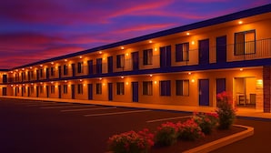 A multi-story motel with a row of rooms, each with a balcony and a small garden area. - Days Inn by Wyndham Rock Springs I-80/Green River (Rock Springs)