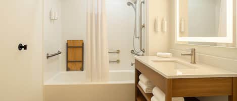 Un baño moderno con bañera, ducha, tocador y espejo.