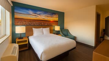 A hotel room with a large bed, two bedside tables with lamps, a chair, and a wall-mounted TV.