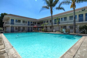 A hotel with a swimming pool, multiple balconies, and palm trees. - Motel 6 Riverside West - Jurupa Valley (Jurupa Valley)