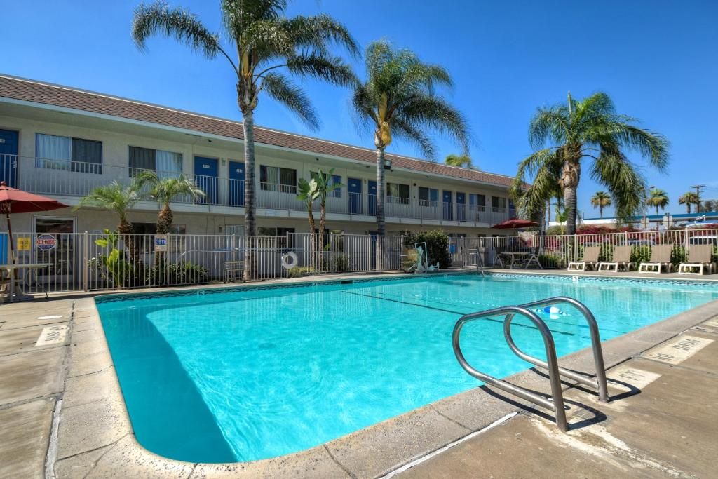 Un hôtel doté d’une piscine, de palmiers et d’un espace clos.