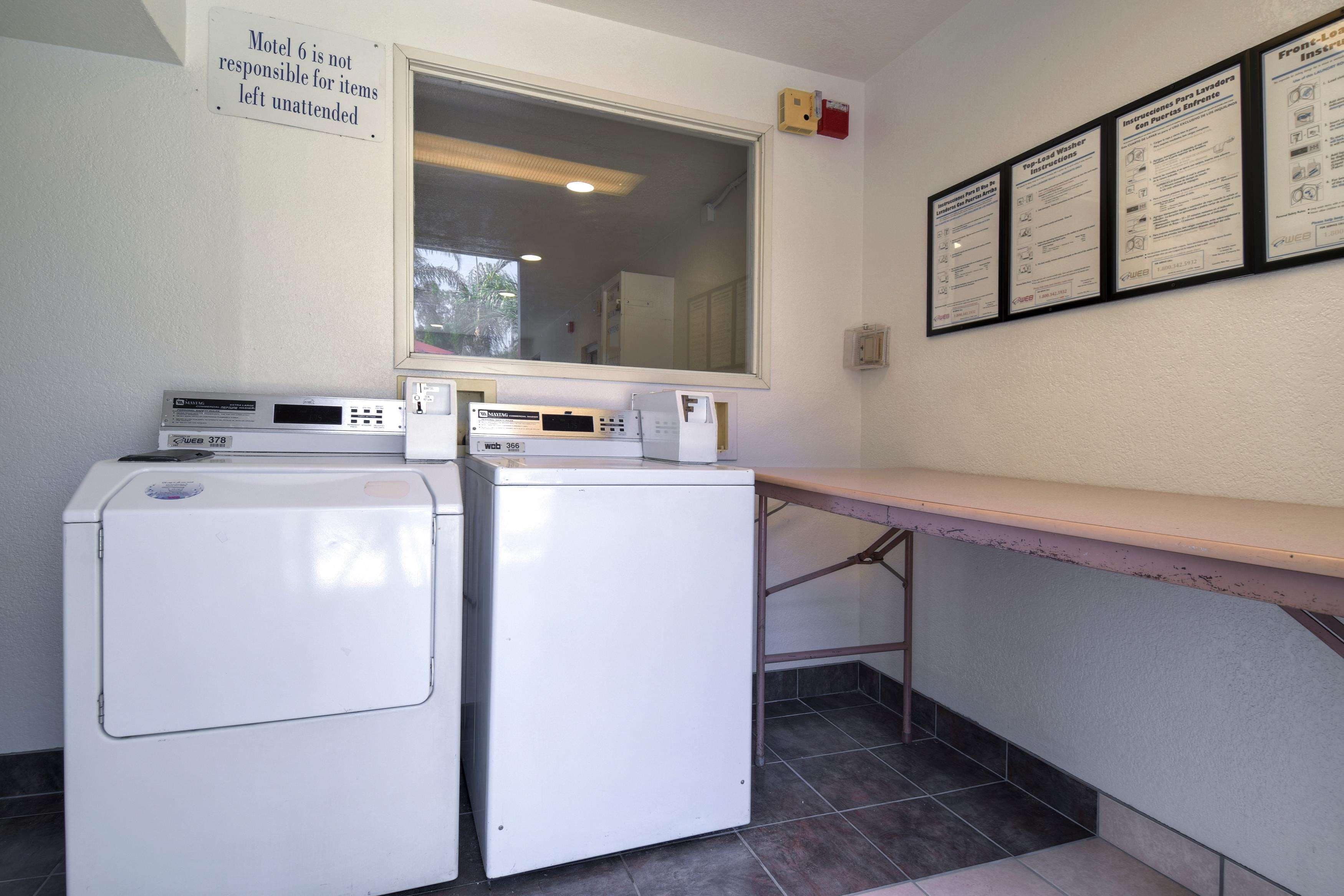 A laundry area with two washing machines, a large window, and informational signs on the wall.